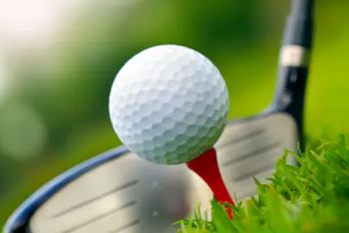 golf ball on a tee with a golf club