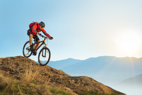 mountain bike rider in red jacket exploring challenging terrain